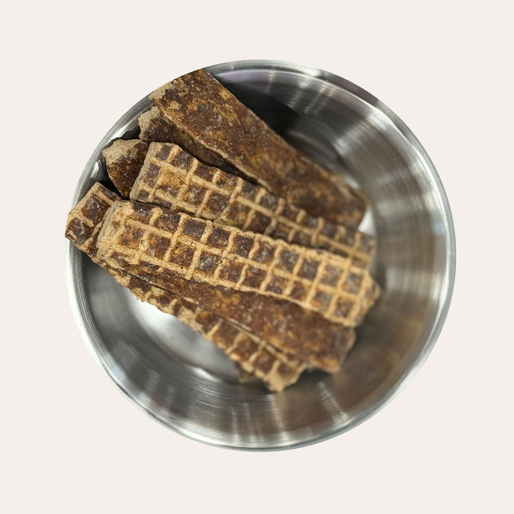 Ernie's Positively Good Ostrich Jerky dog treats placed in a metal bowl.